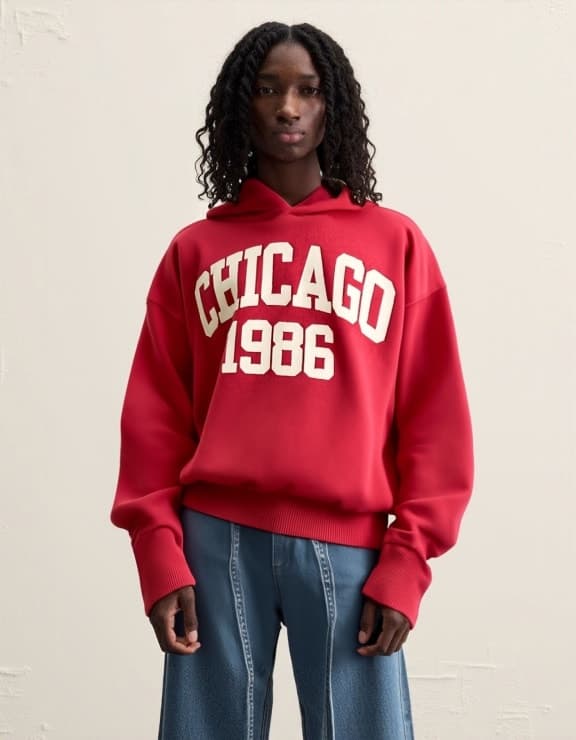 A model wearing a red hoodie with "Chicago 1986" text design