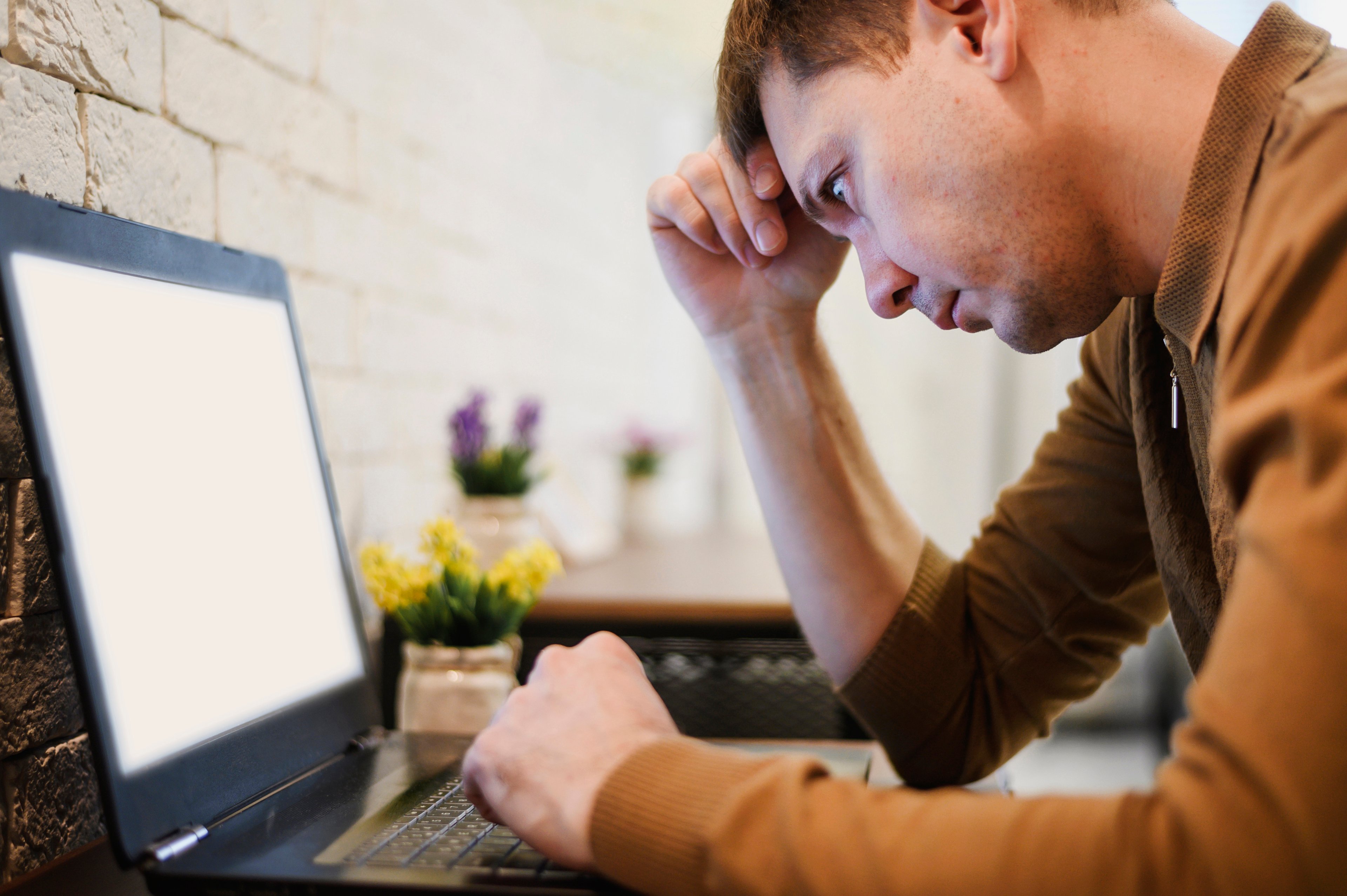 A frustrated man staring at a slow loading laptop.