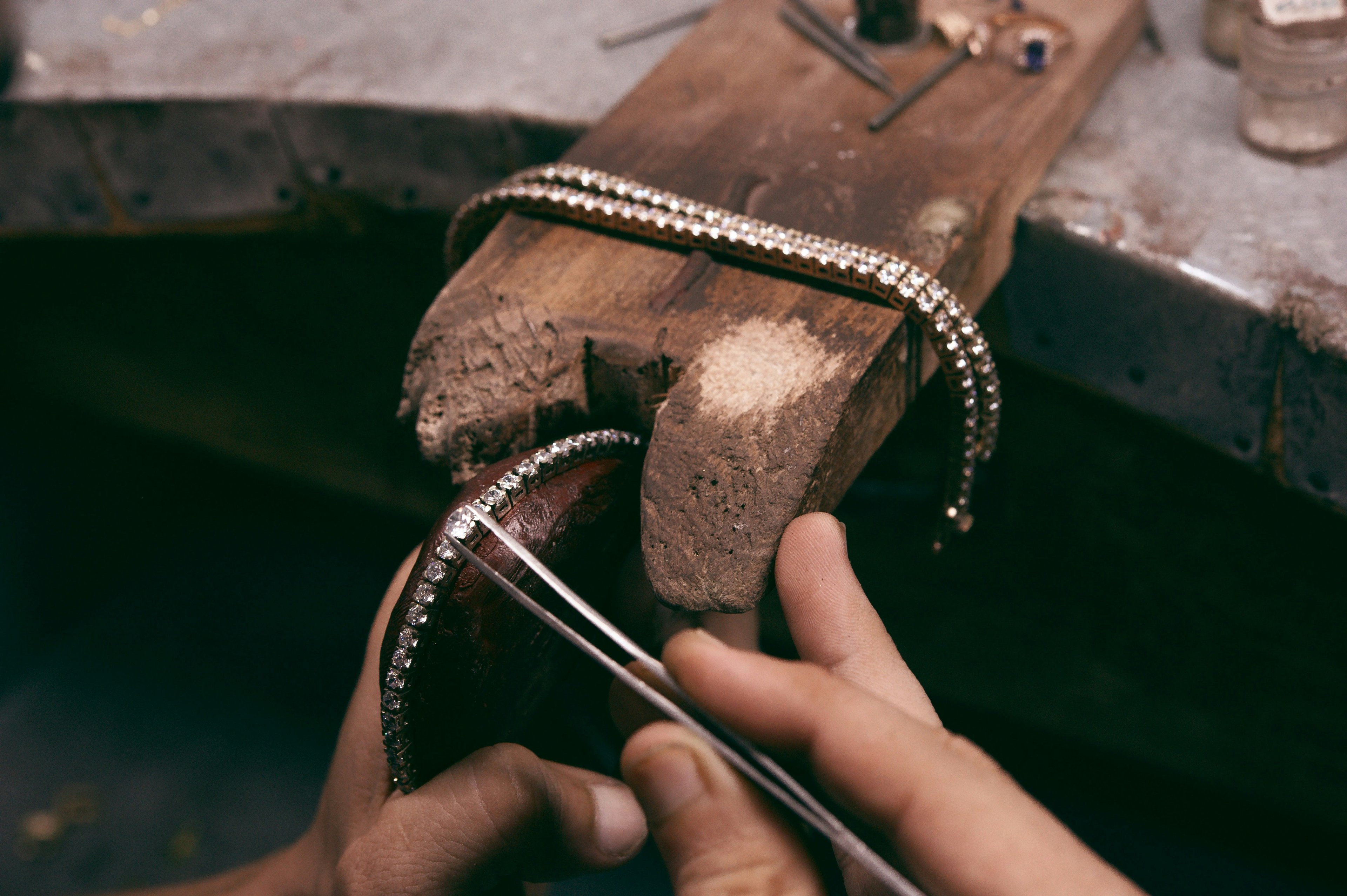 A jewelry maker crafting a diamond tennis bracelet by hand.