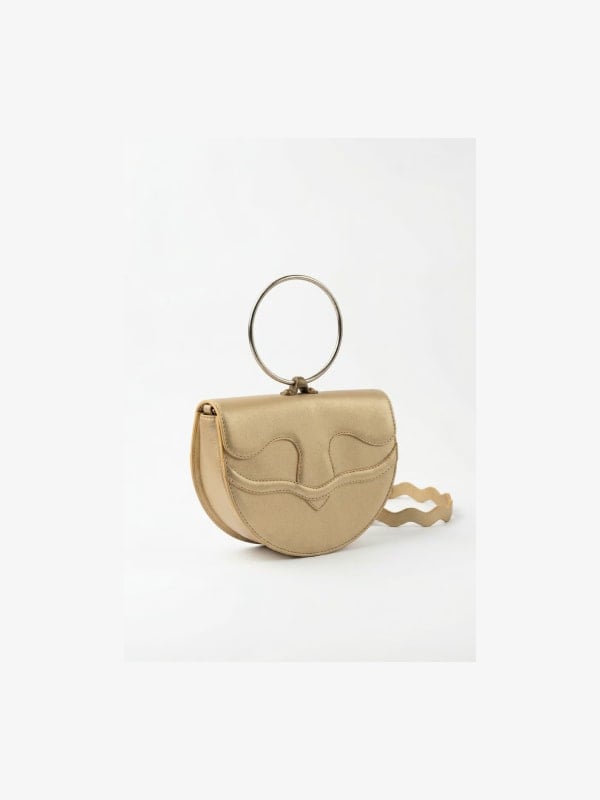 Gold metallic leather mini saddle bag with a top ring handle and curved flap closure, shown in three-quarter view on a white background.