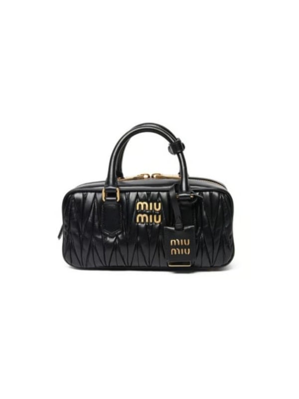 Black quilted Miu Miu top-handle bowling bag with gold logo lettering and matching leather luggage tag, shown front-facing on a white background.