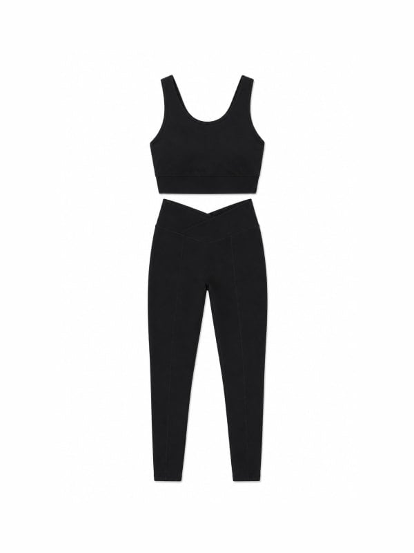 Black ribbed sports crop top and matching crossover-waist leggings, displayed flat on a white background.