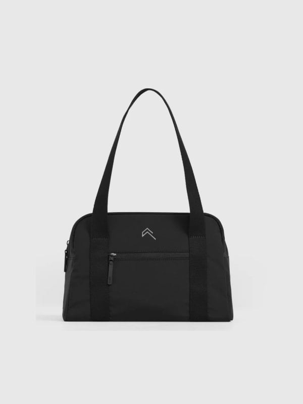 Black nylon gym duffel bag with shoulder straps, front zip pocket, and small chevron logo, shown front-facing on a light grey background.