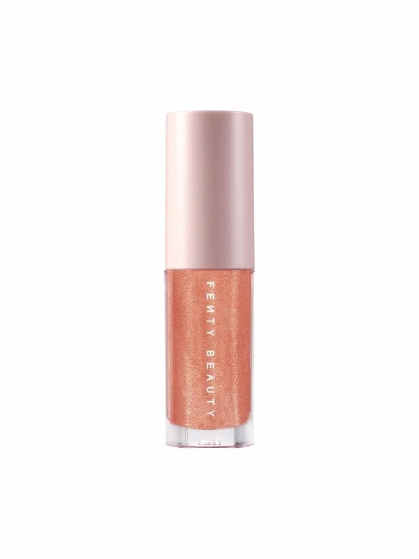 Fenty Beauty Gloss Bomb shimmer lip luminizer in a copper-rose shade with a pale pink cap, shown standing on a white background.