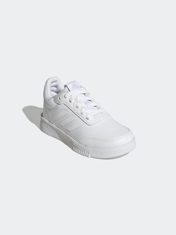 White Adidas Tensaur low-top sneaker with three stripes, shown in three-quarter view on a light grey background.