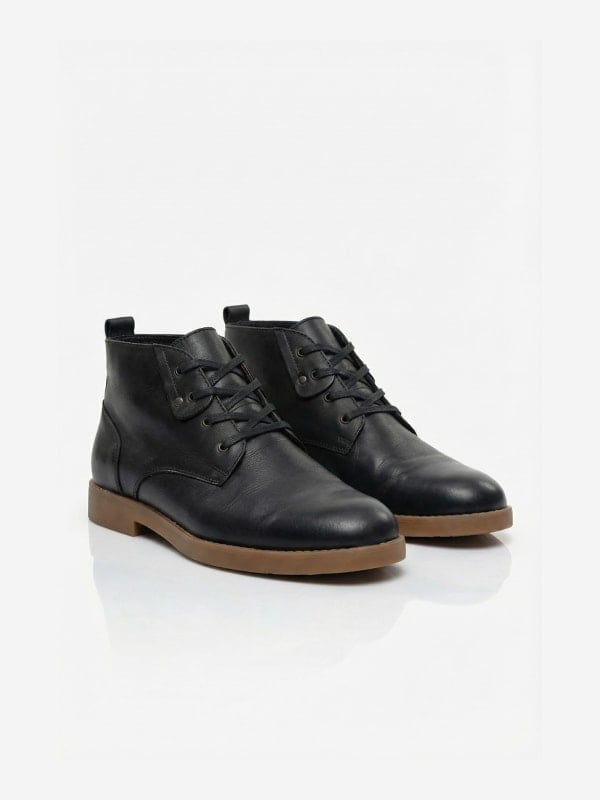 Pair of black leather chukka boots with gum soles and lace fronts, shown in three-quarter view on a white background.