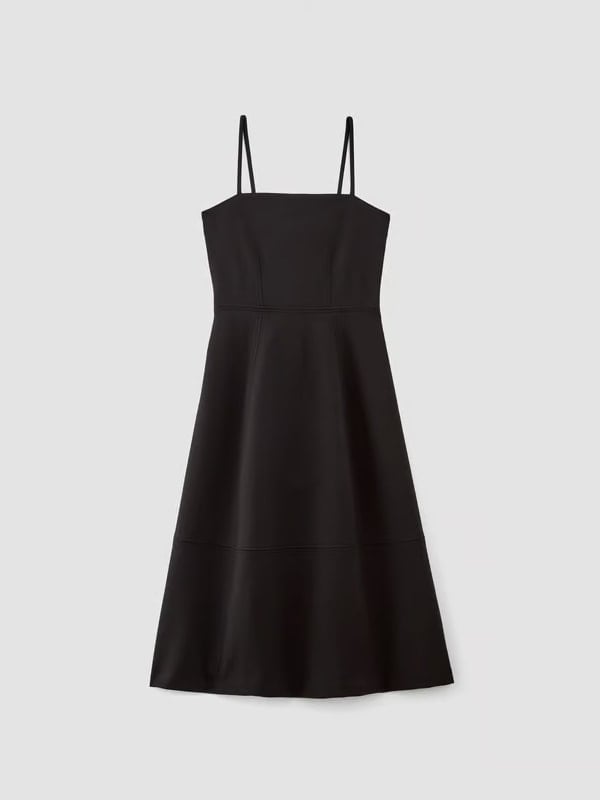 Flat lay of a black midi dress with thin shoulder straps and a fitted bodice, displayed on a white background.