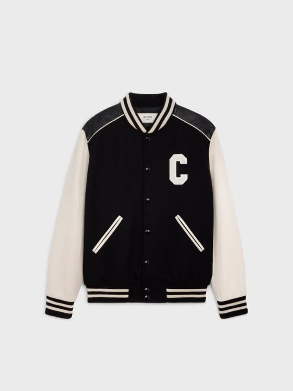 Black and cream Celine varsity jacket with a white C letter patch and striped trims, displayed flat on a light background.