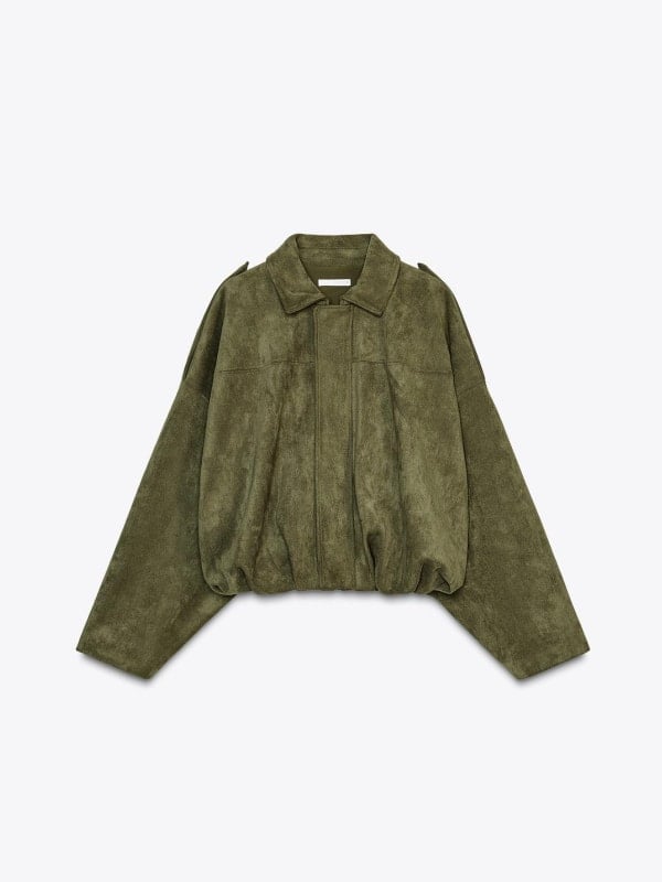 Olive green suede bomber jacket with a collar and zip front, displayed flat on a deep green background.