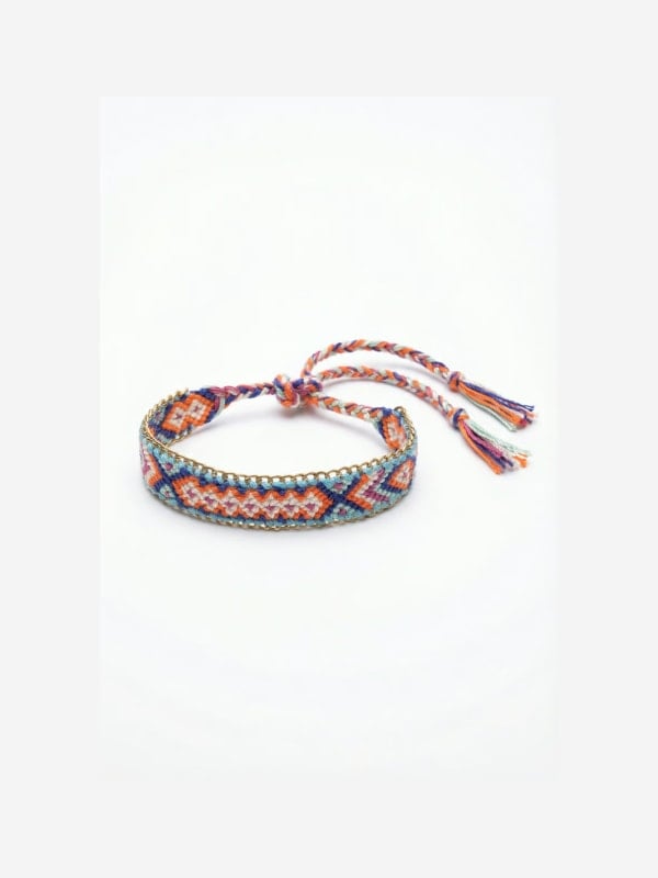 Woven friendship bracelet with a multicoloured aztec pattern, gold chain trim, and tassel ties, displayed flat on a white background.