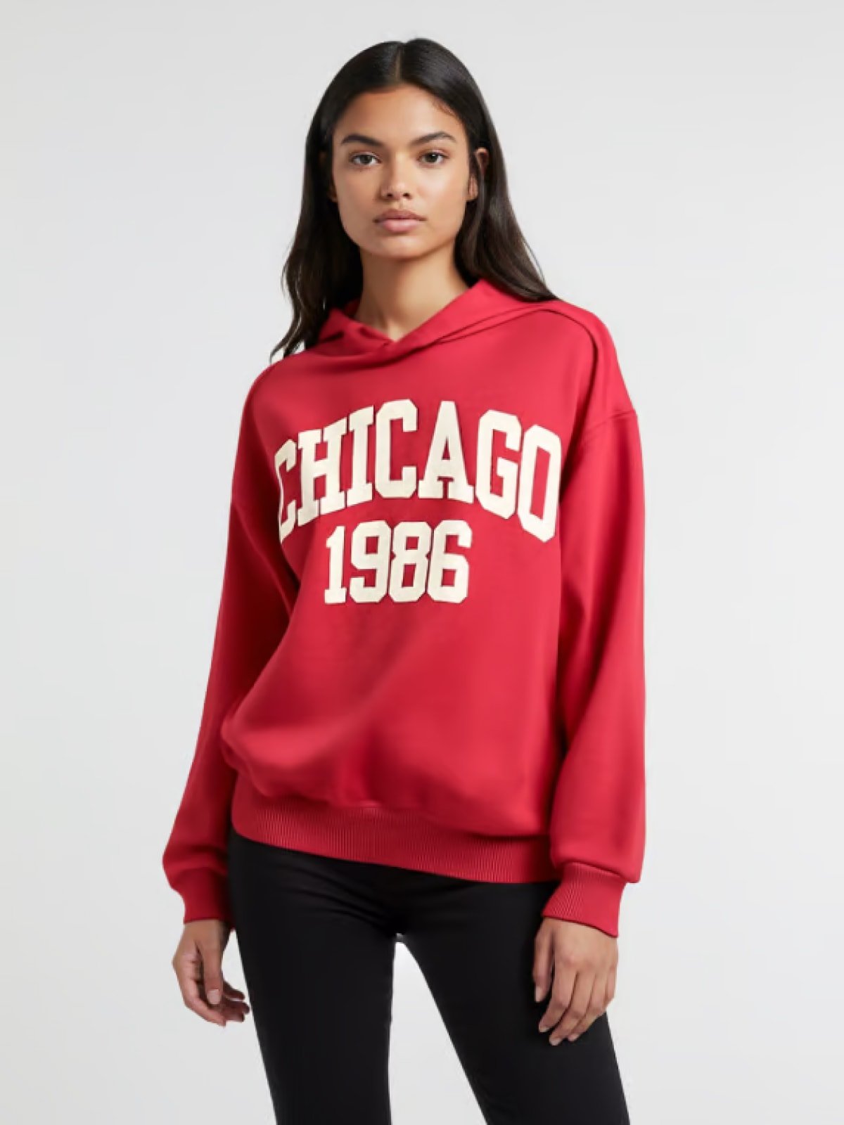 Woman wearing a red hoodie with ‘Chicago 1986’ print, standing against a light background