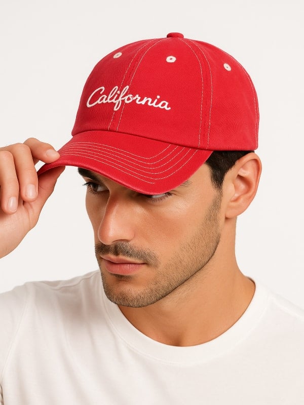 Man wearing a red baseball cap with ‘California’ embroidered in white, paired with a plain white t-shirt.