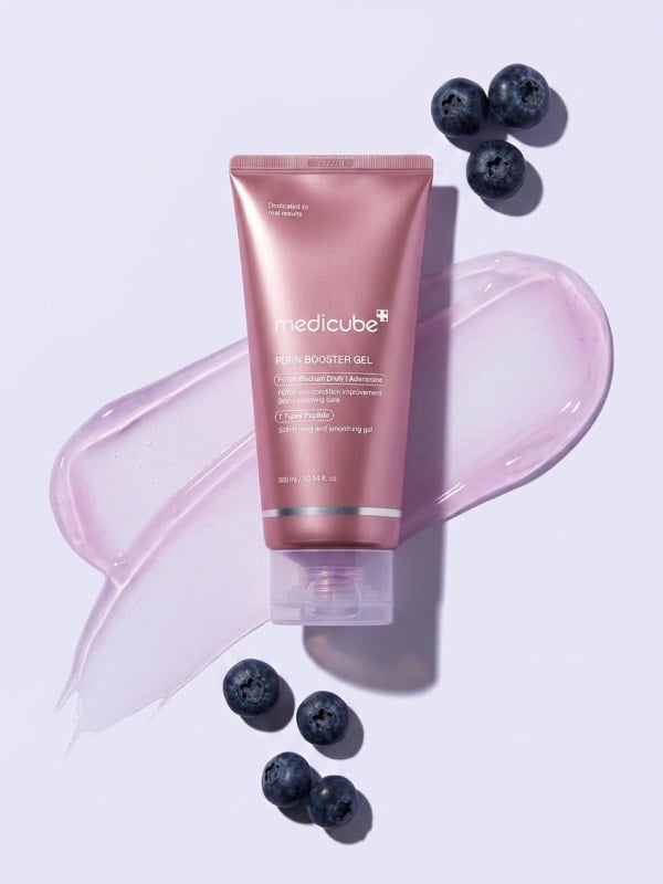 Pink Medicube PDRN Booster Gel tube laid on a lavender background with a pink gel swatch and scattered fresh blueberries.