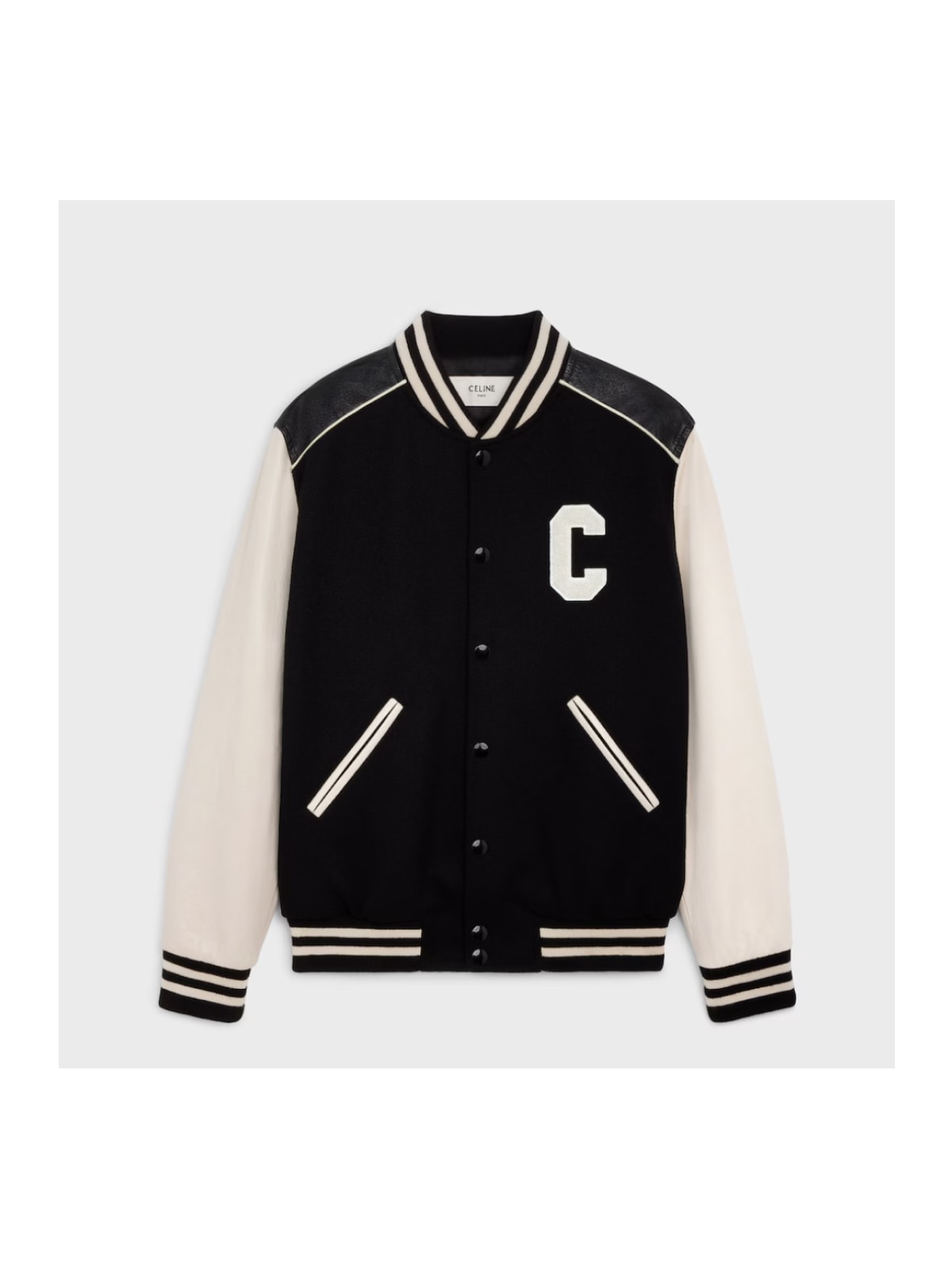 Black and cream Celine varsity jacket with a white C letter patch, cream leather sleeves, and striped knit trims, displayed flat on a light grey background.