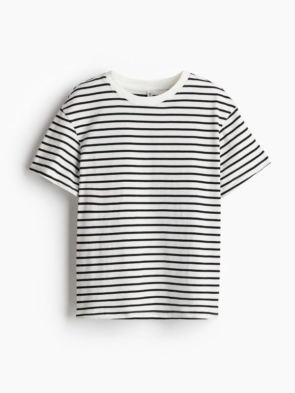 White t-shirt with thin black breton stripes and a classic crew neckline, displayed flat on a light grey background.