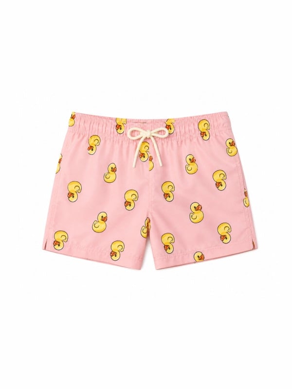 Pink swim trunks printed with yellow rubber duck illustrations, finished with a cream drawstring tie at the waist, displayed flat on a white background.